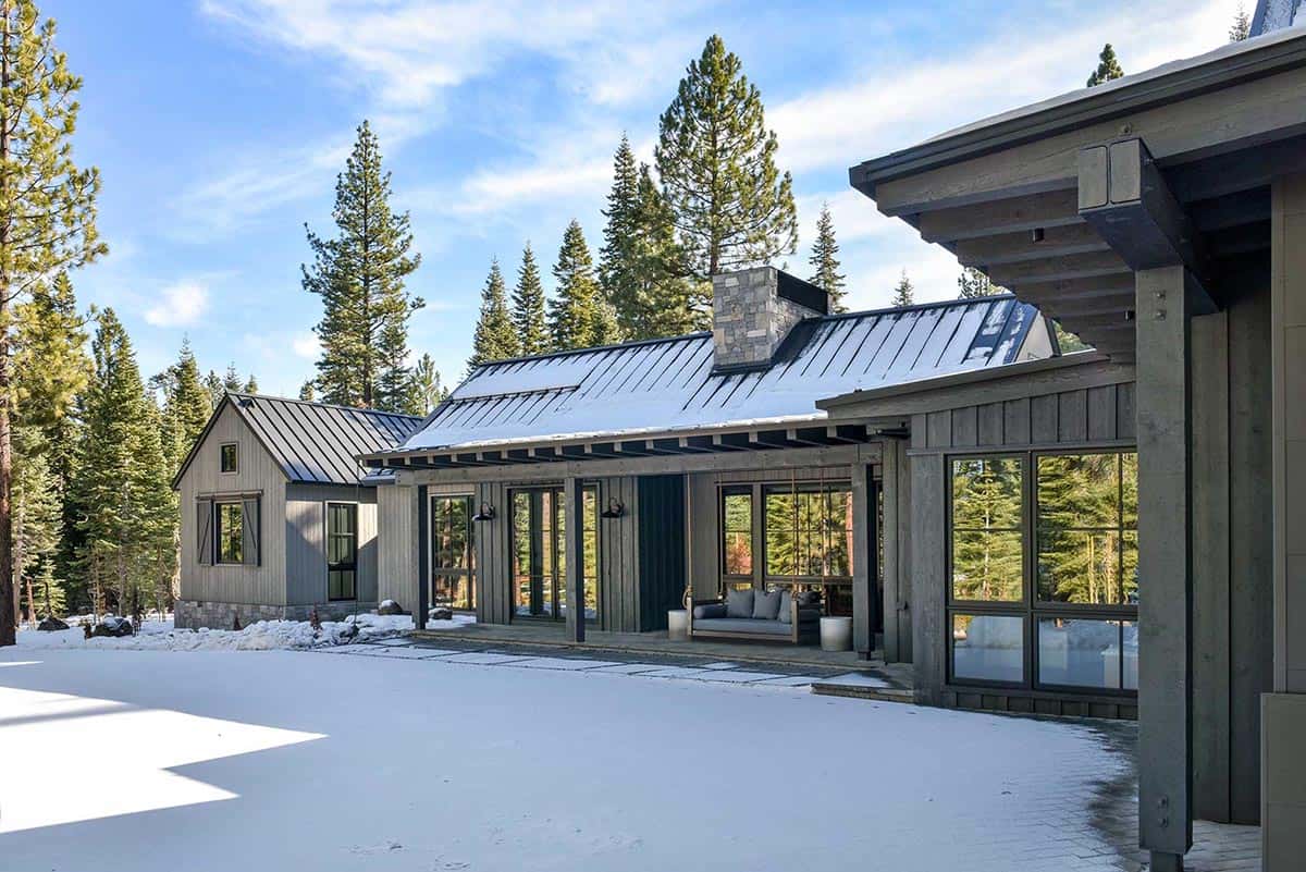 Snow-covered exterior with metal roof, covered porch, and hanging swing