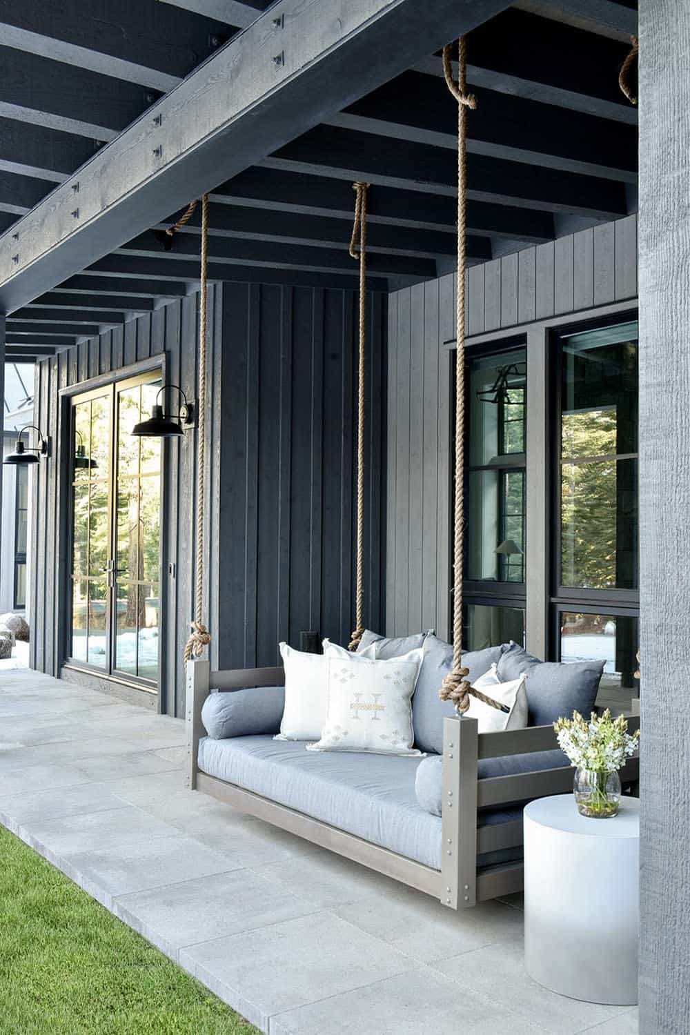 Covered porch with hanging daybed swing and dark wood-clad exterior