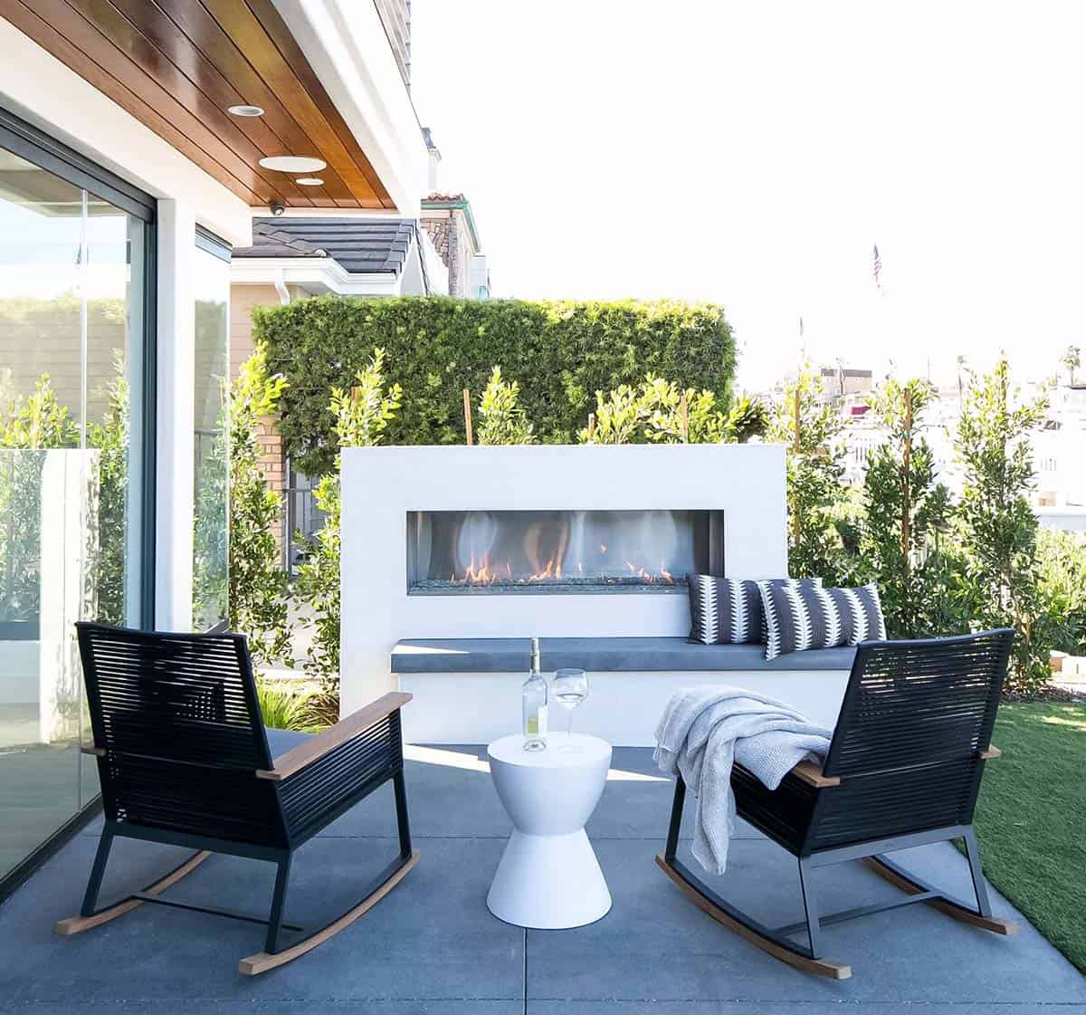 Modern outdoor fireplace with built-in bench on a waterfront patio