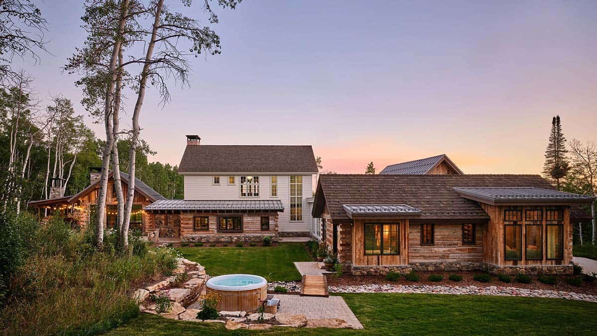 Backyard view of main house, cabin, and hot tub at dusk