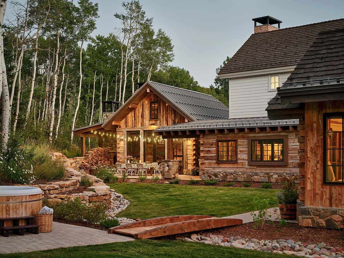 Log cabin exterior with stone patio and wooden footbridge