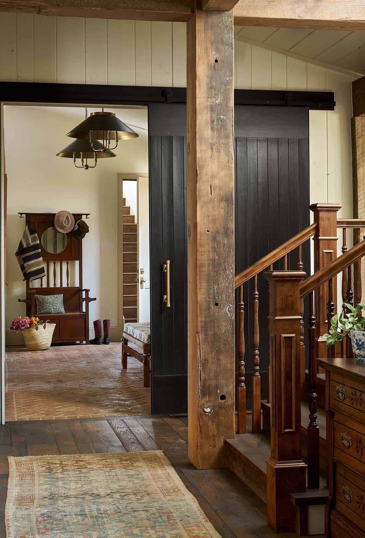 Black sliding barn door beside staircase with wood railing