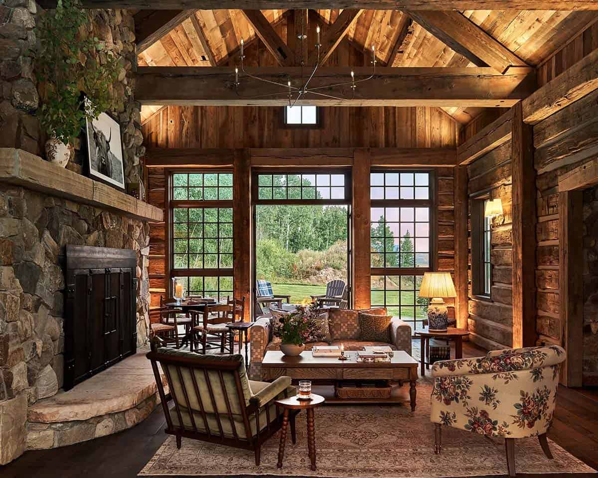 Log cabin great room with fireplace and forest view
