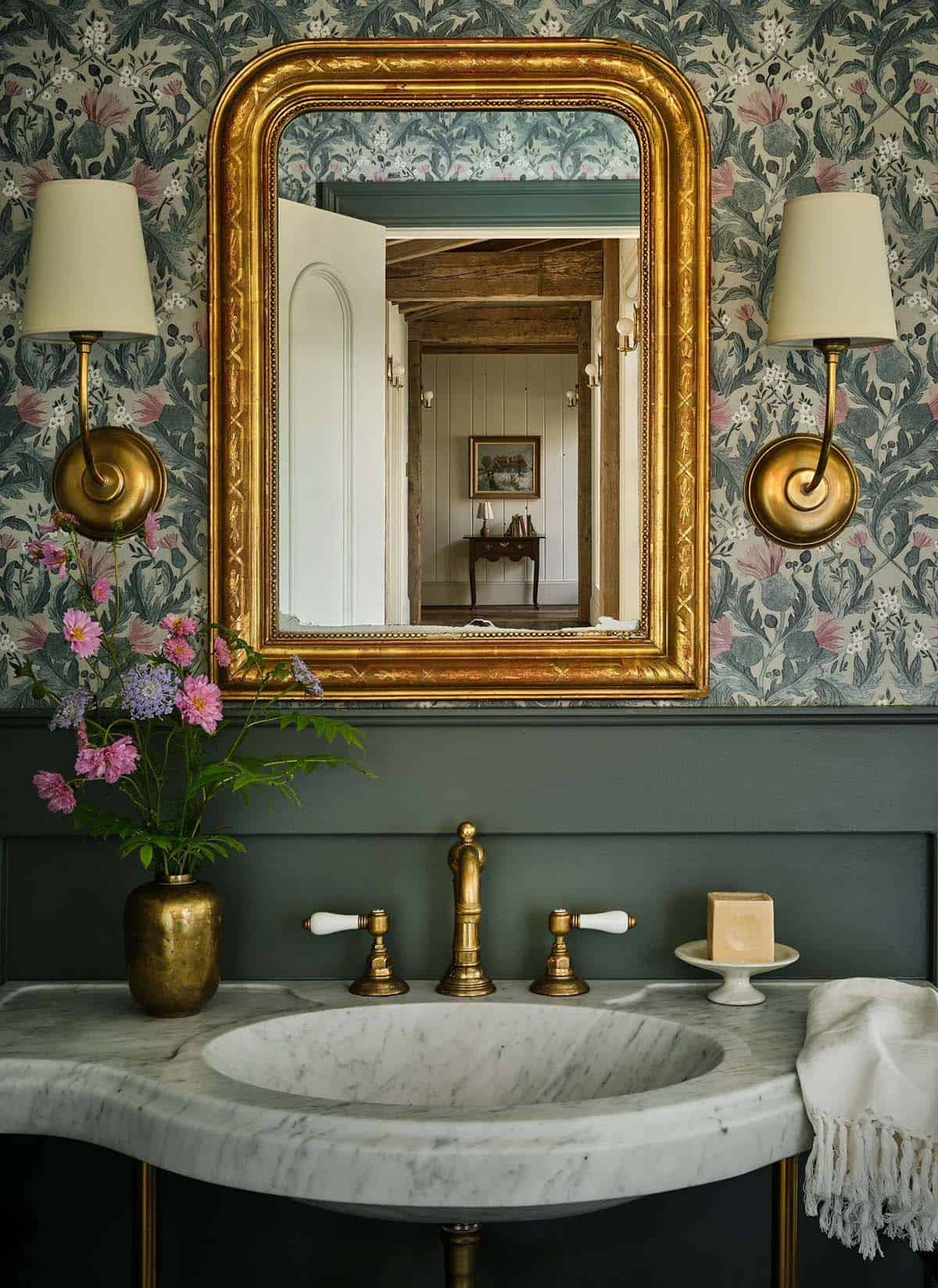 Powder room with gilded mirror and brass wall sconces
