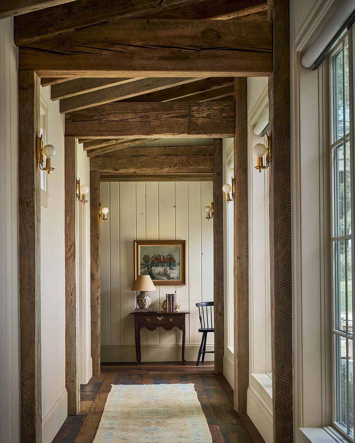 Wood-beamed hallway leading to console table and armchair