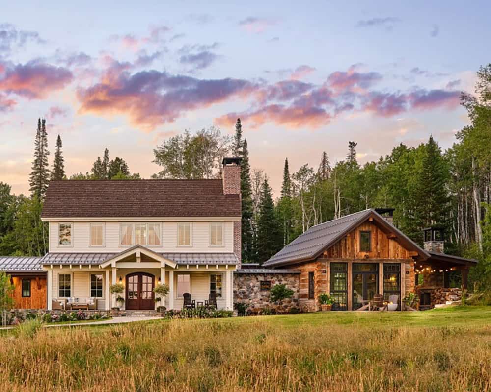 Farmhouse and rustic cabin exterior view across open meadow