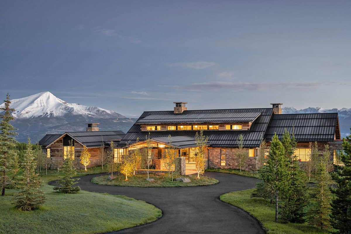 Ski lodge exterior at dusk with snow-capped mountain backdrop