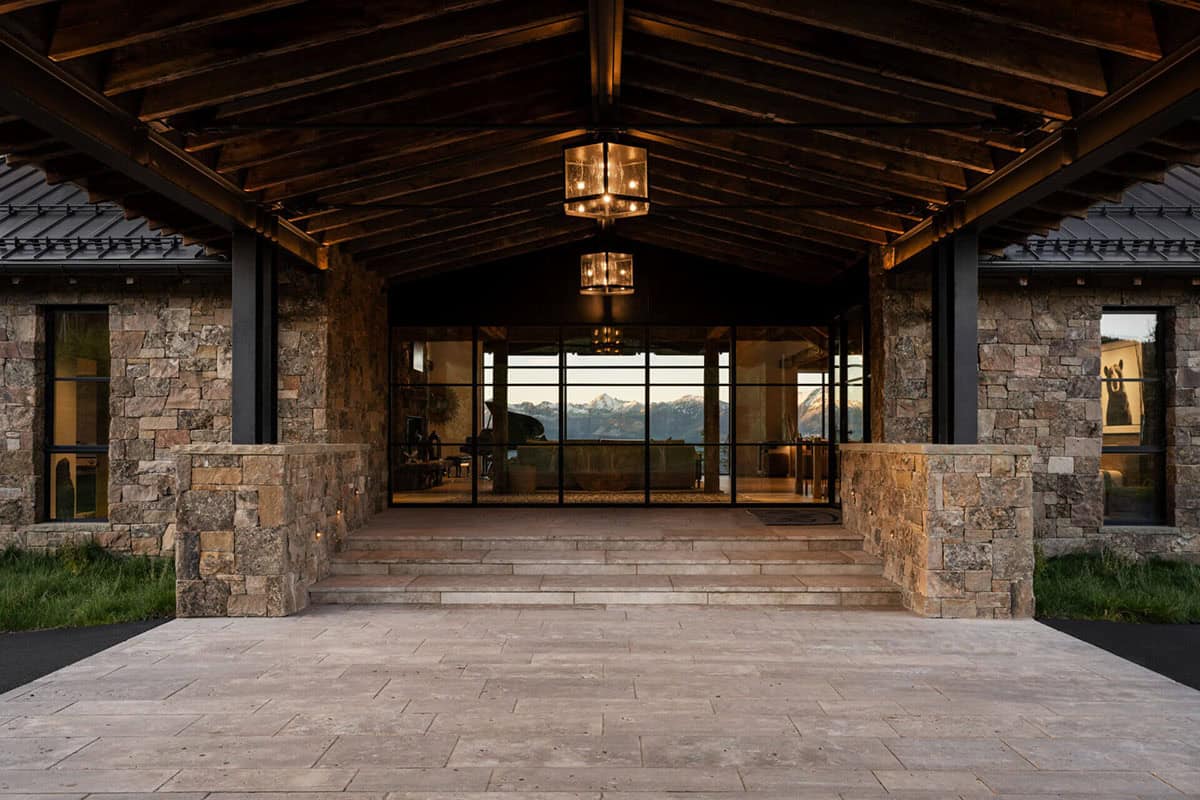 Covered stone entryway framing mountain view through glass doors