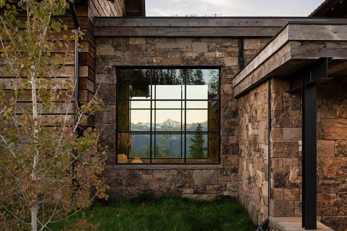 Square window reflecting snow-capped peak in stone exterior wall