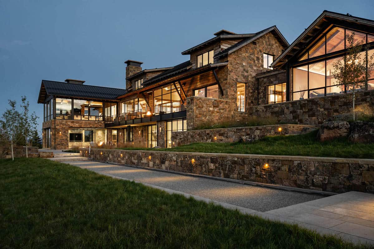 Evening exterior view of stone terrace and illuminated glass walls
