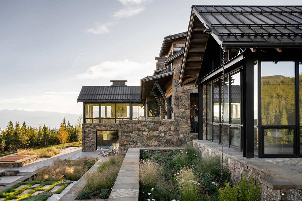 Stone and glass wing overlooking mountain meadow at dusk