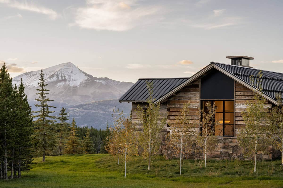 Rustic wood cabin exterior with snow-capped peak beyond