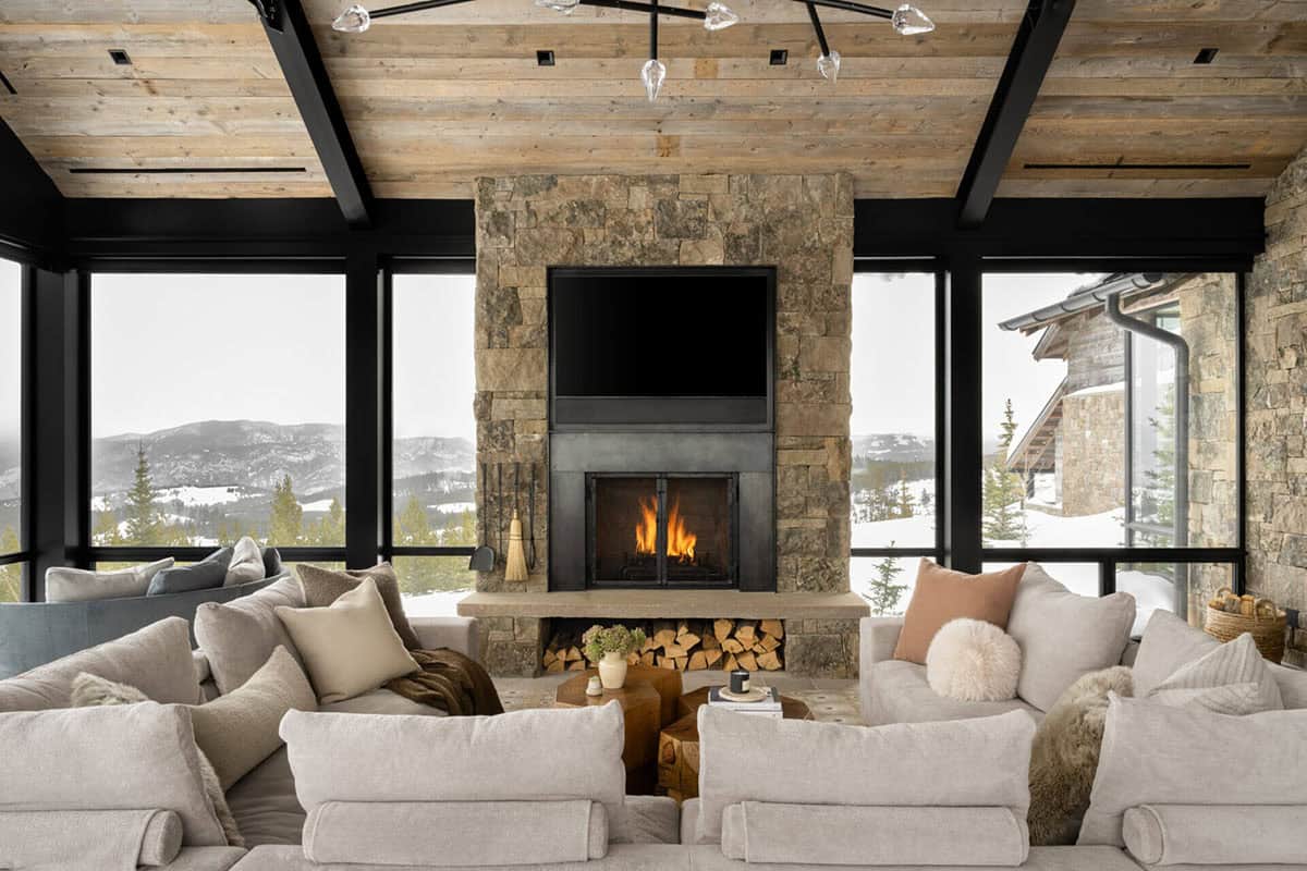 Living room stone fireplace framed by snowy mountain windows