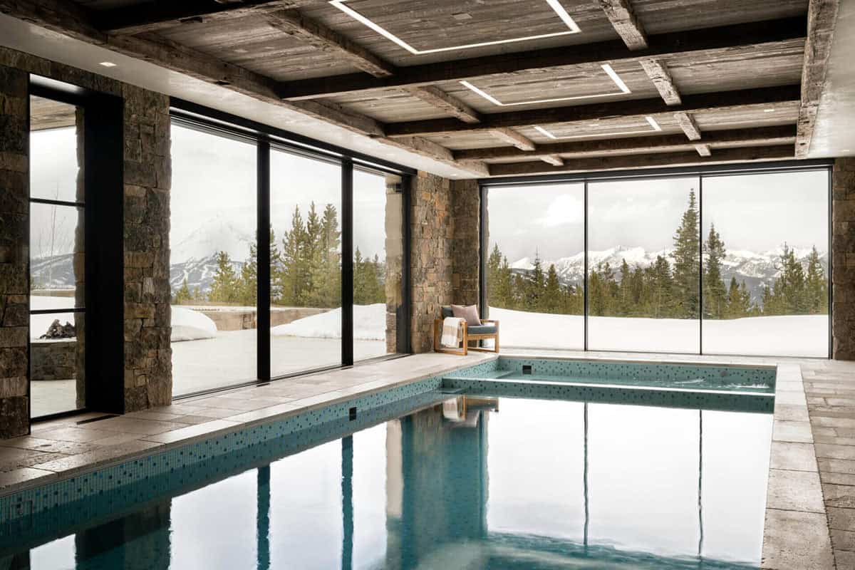 Indoor pool and spa with stone walls and forest views