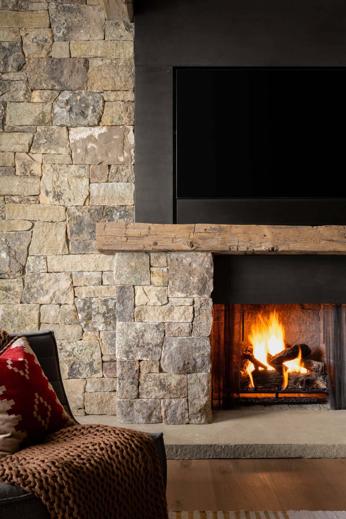 Detail of stacked stone fireplace with rustic wood mantel