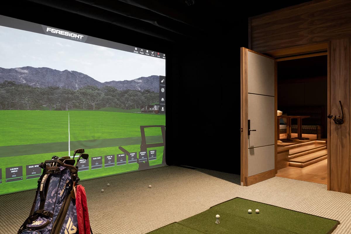 Golf simulator room with screen and adjacent lounge area