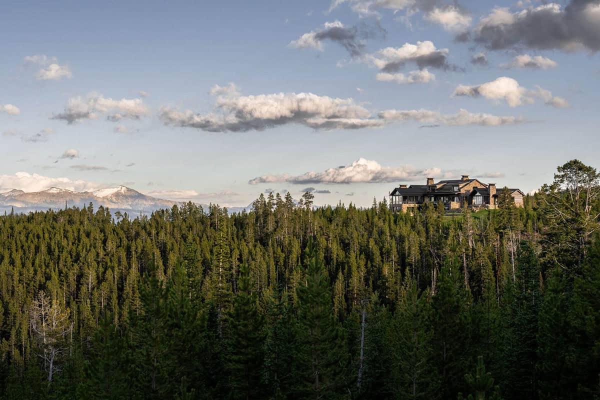 Distant view of ski lodge perched above dense pine forest