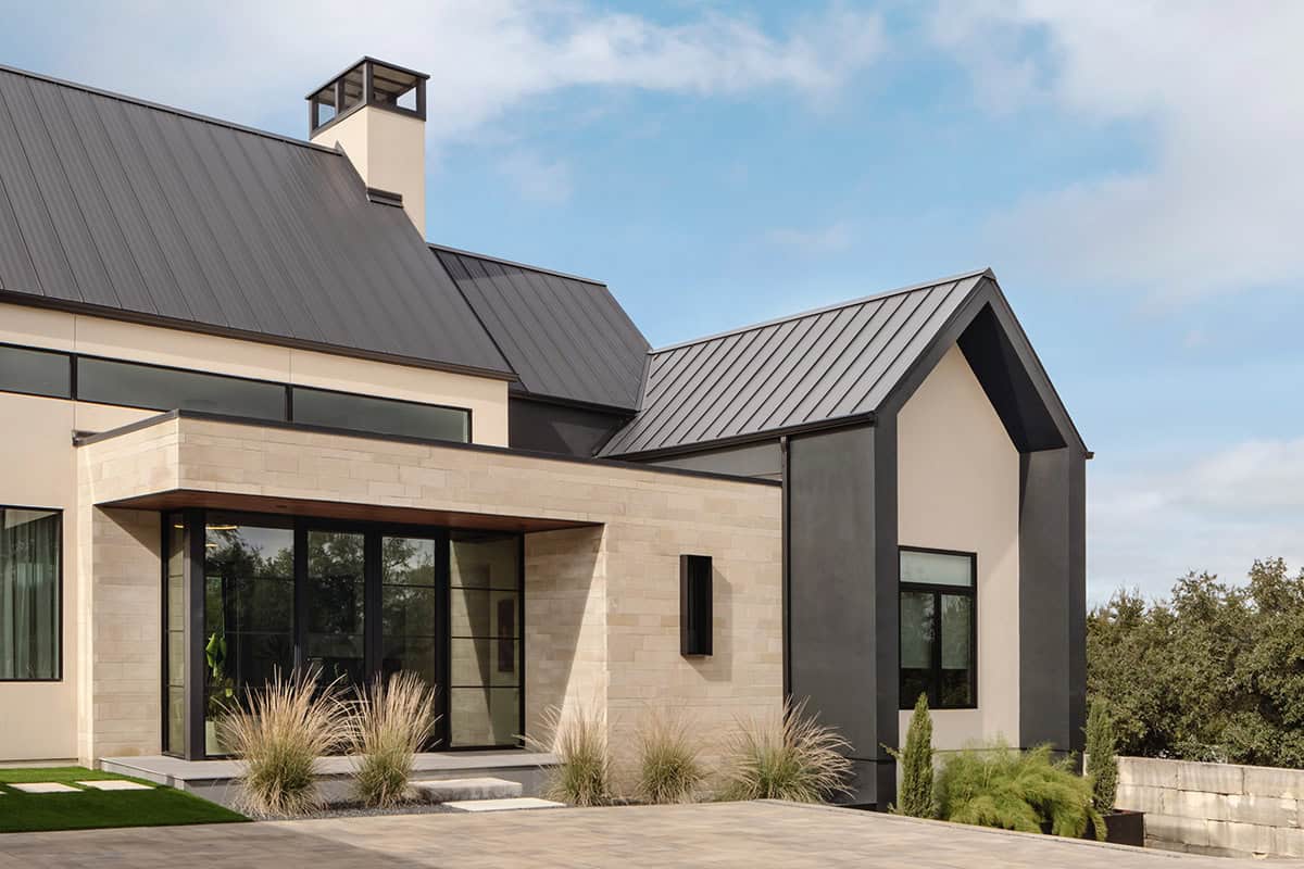 Standing seam metal roofline meets stone-clad entry with black steel trim