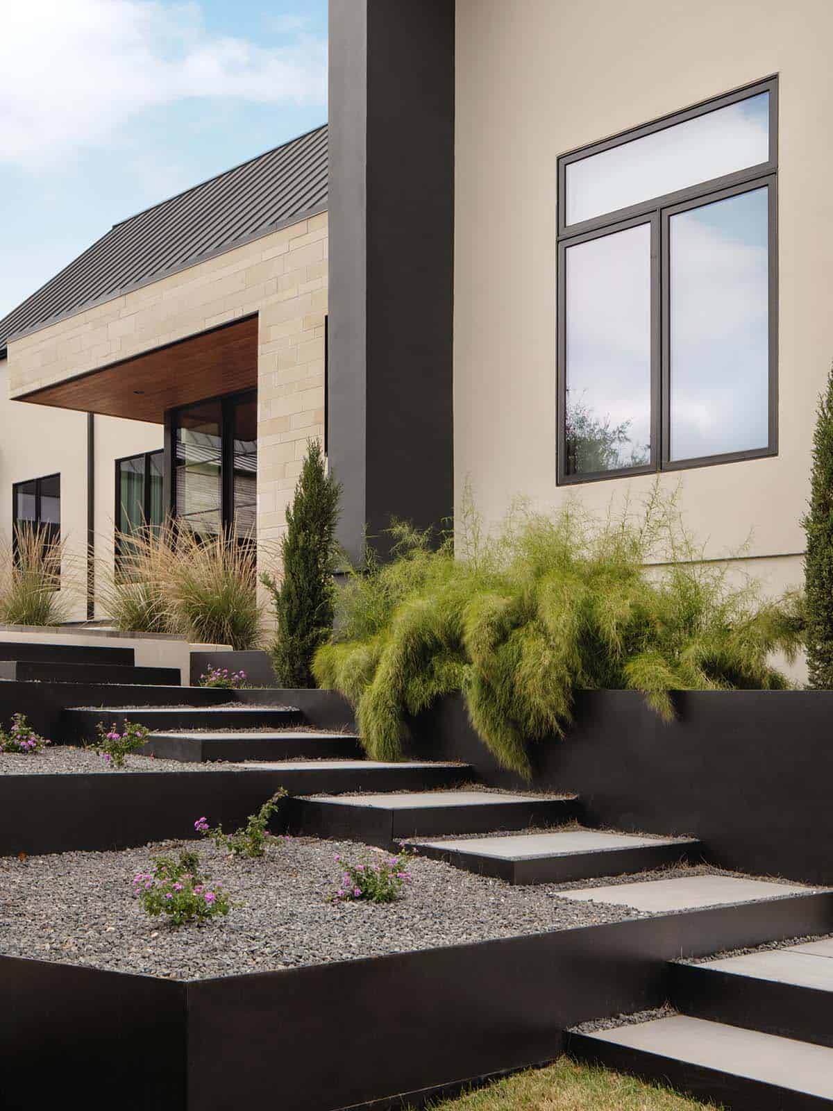 Black steel garden steps cascade through gravel beds with wildflowers
