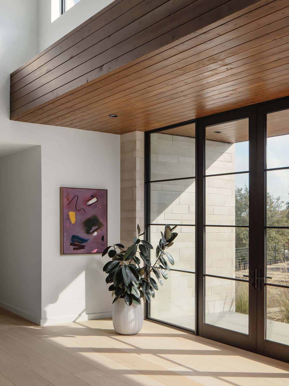 Danish home entry with cedar-clad ceiling and faux plant decor with abstract art on the wall
