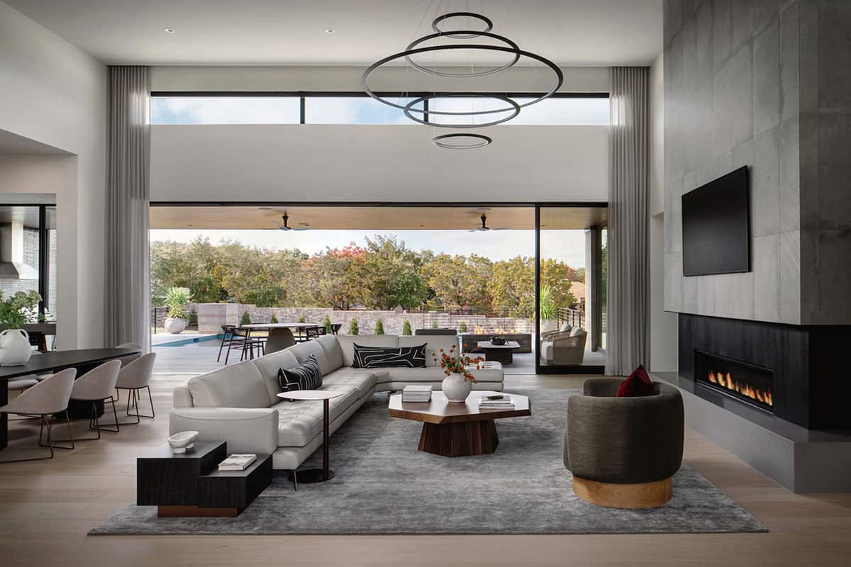 Open-concept living room with ring chandelier overlooking covered patio and pool