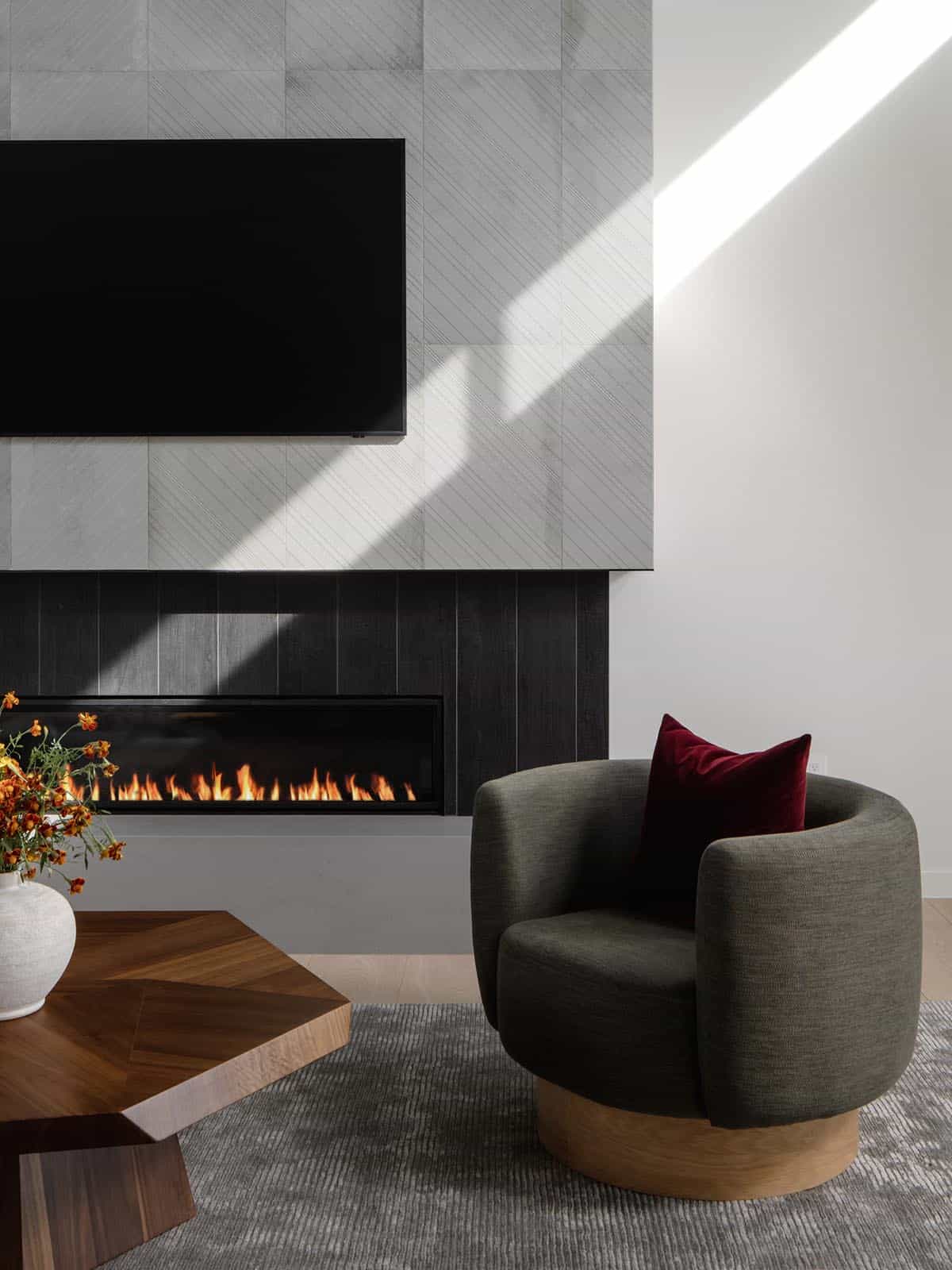 Charcoal tile fireplace surround beside a swivel chair with velvet pillow