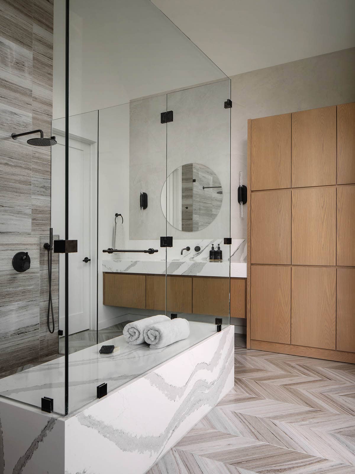 Spa bathroom with herringbone tile floor and glass-enclosed walk-in shower