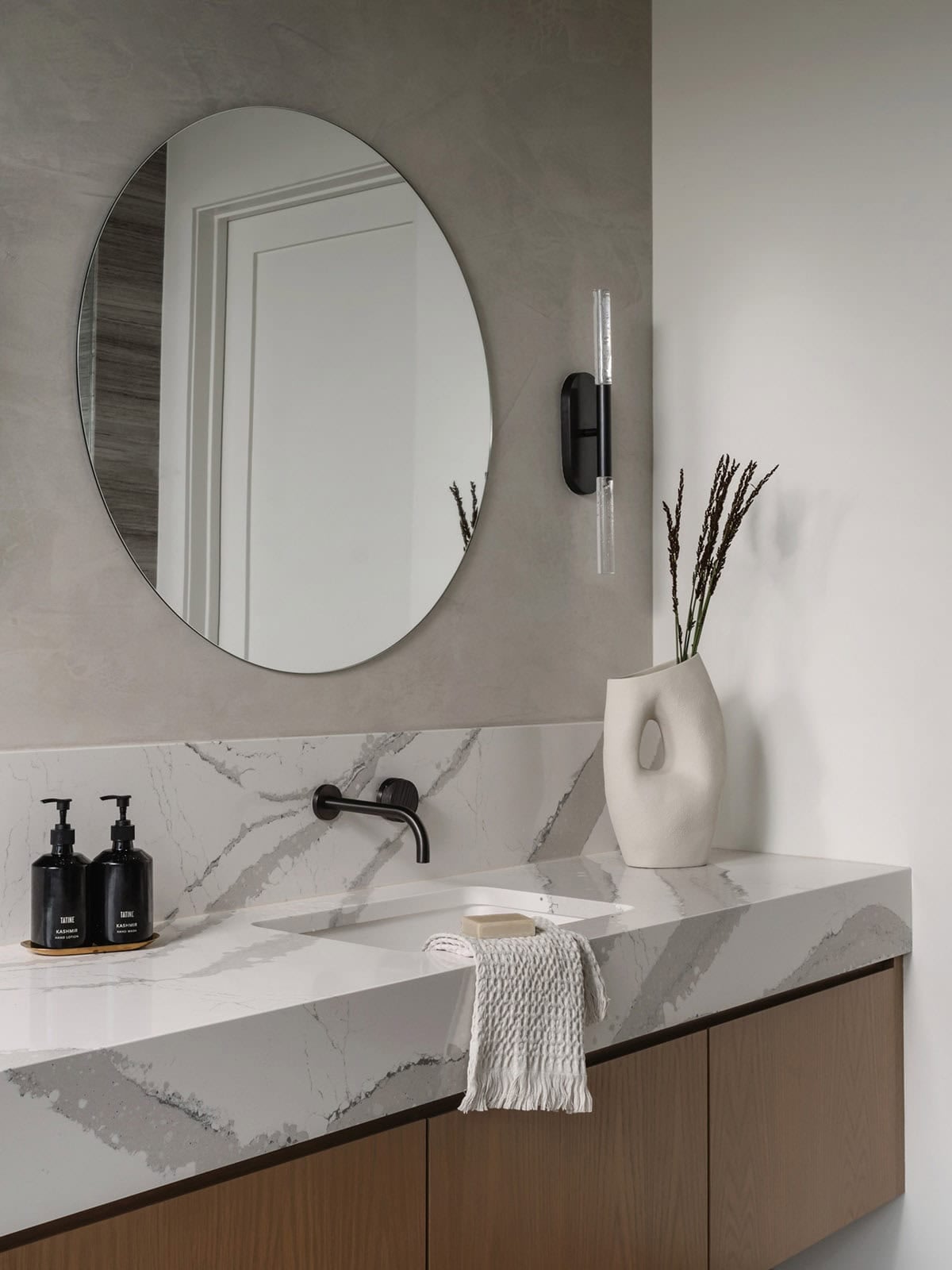 Floating marble vanity with round mirror and black glass sconces