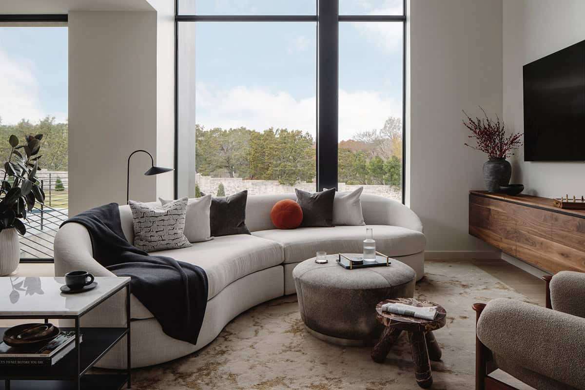 Curved bouclé sectional sofa facing a walnut media console and TV