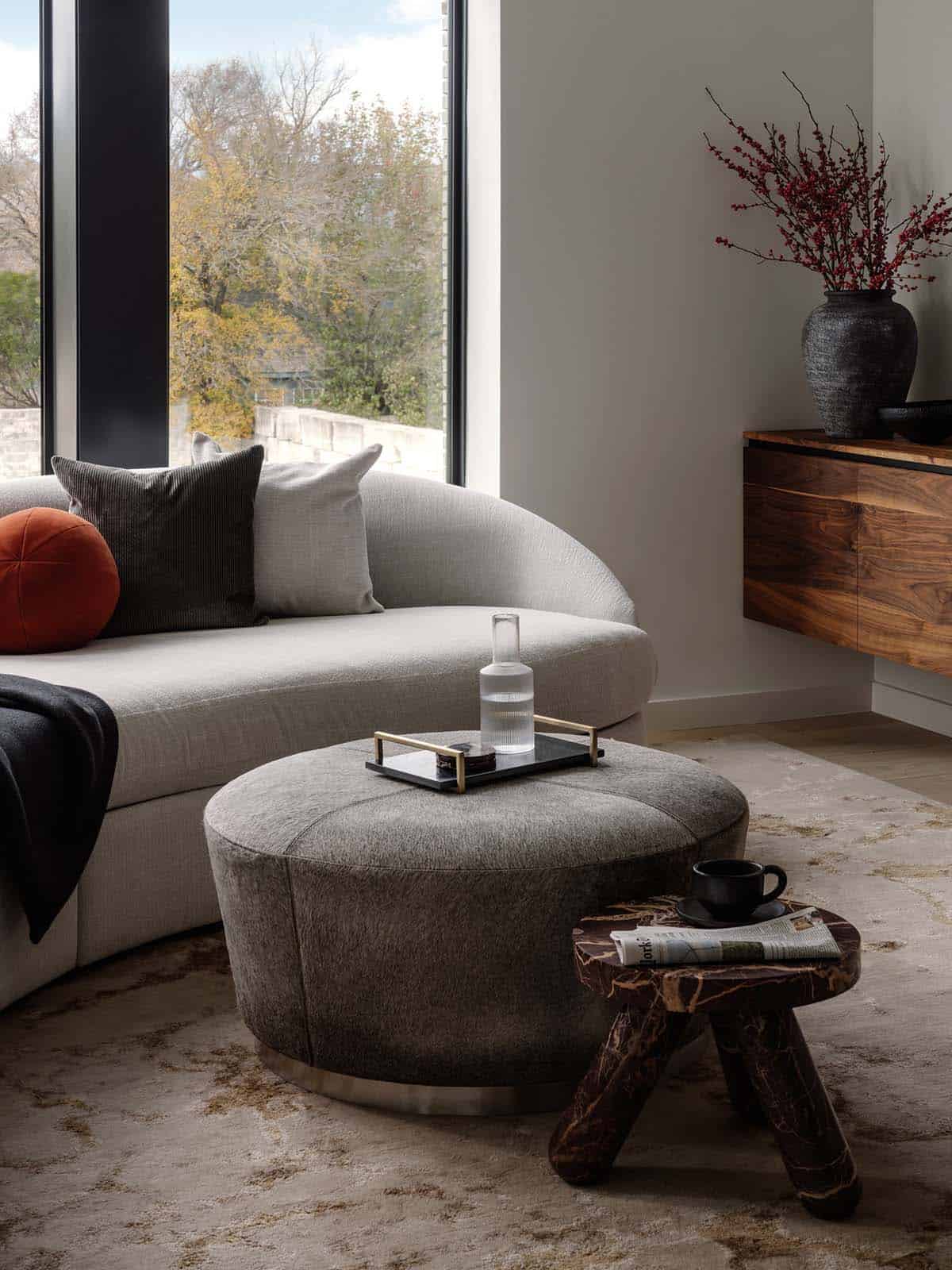 Cowhide ottoman and marble side table beside a curved gray sofa