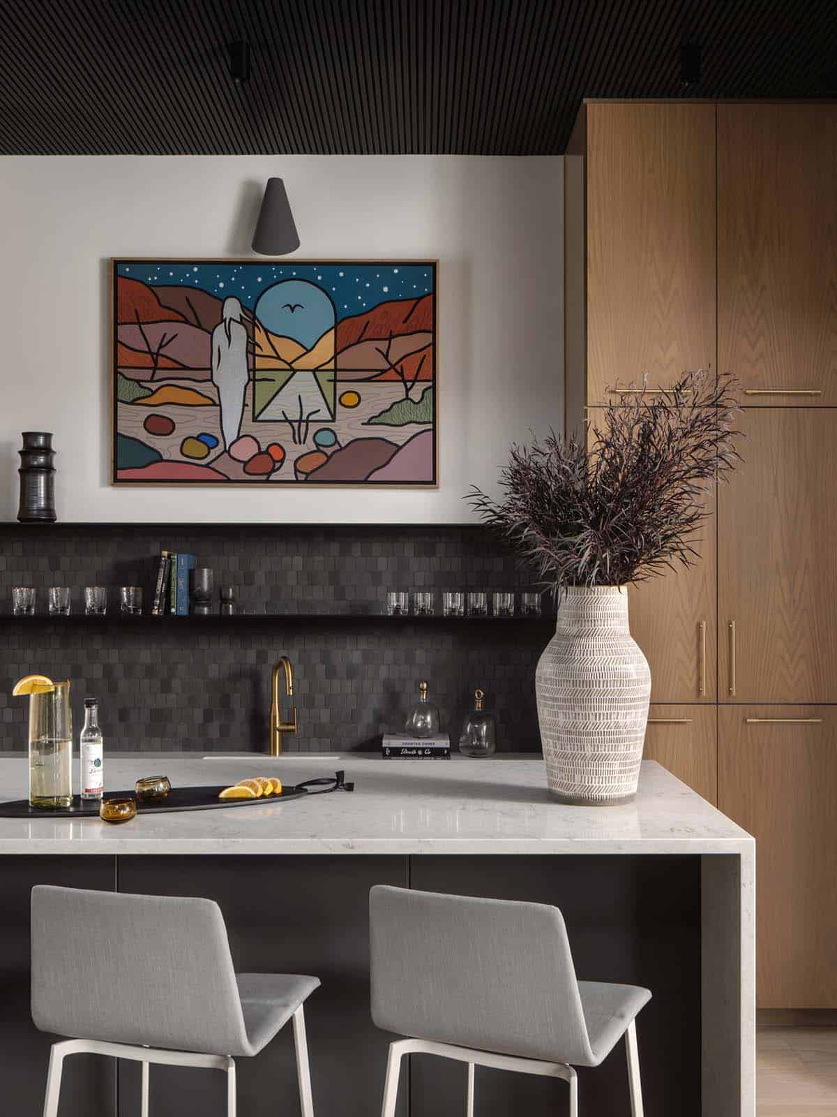 Dark tiled bar nook with brass faucet and colorful desert artwork