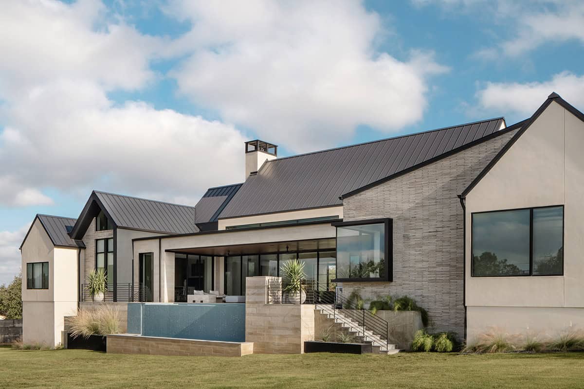 Rear elevation with elevated spa, stone patio, and covered outdoor living