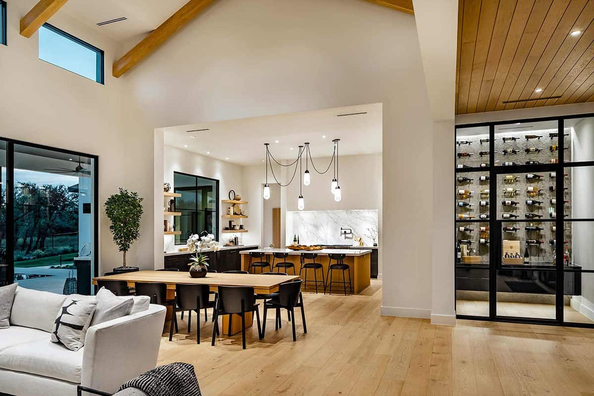 Dining area overlooking kitchen with glass wine display at dusk