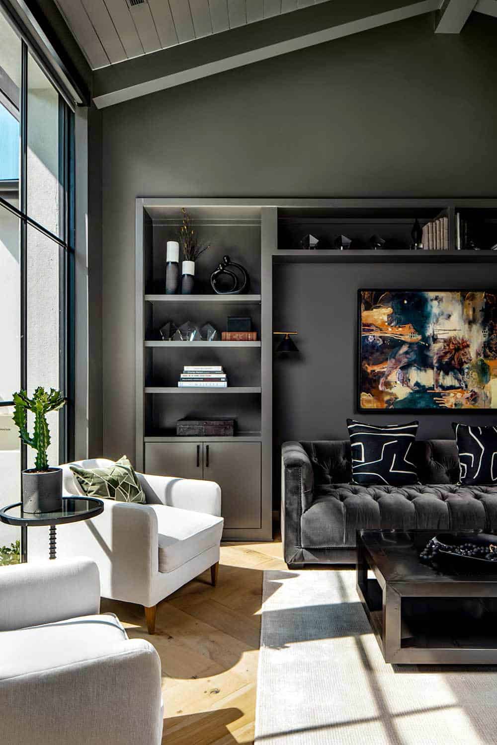Built-in bookshelves and tufted sofa in dark charcoal sitting room