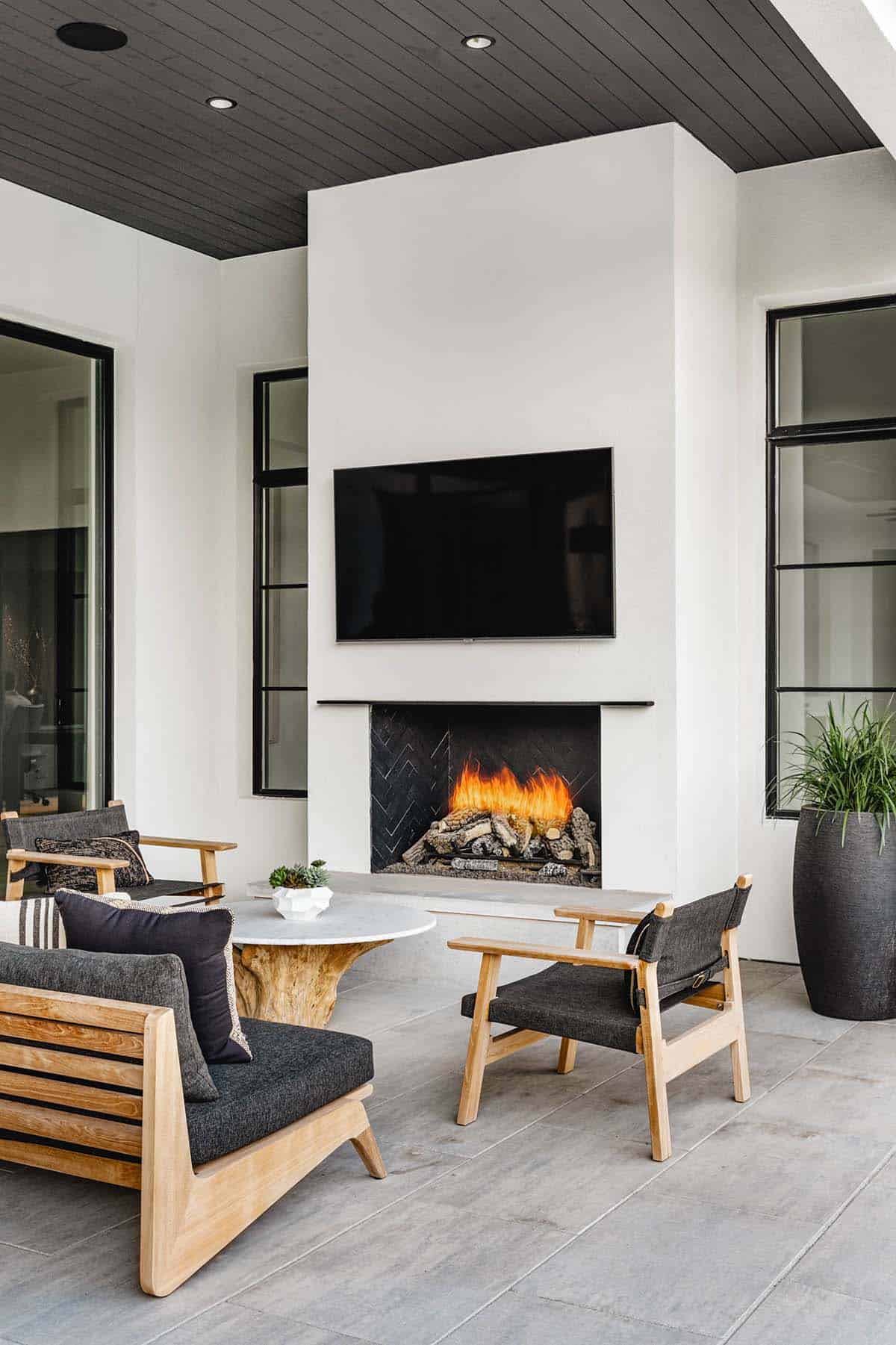 Outdoor living area with fireplace, mounted television, and teak seating