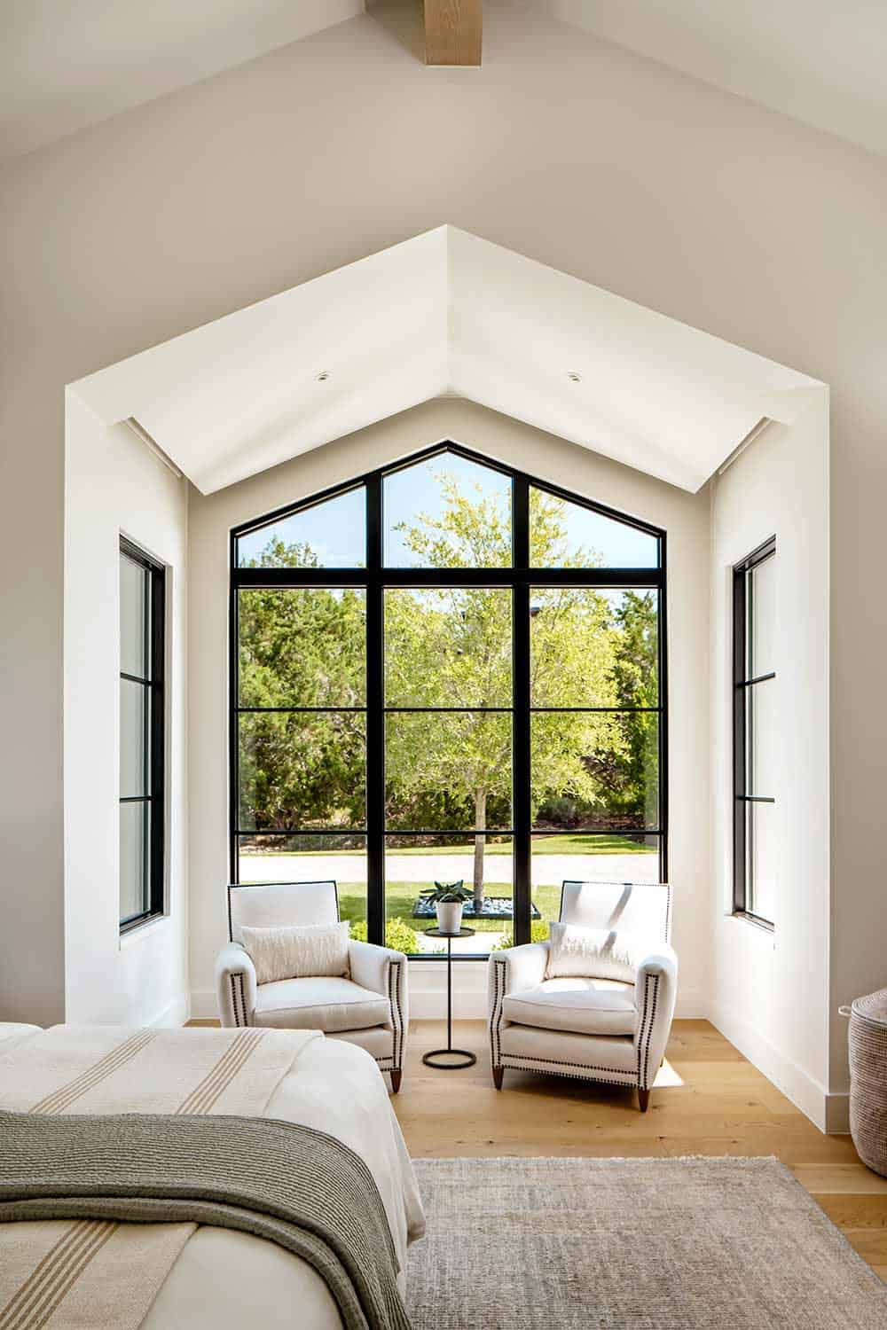 Bedroom sitting nook with peaked window overlooking mature landscaping