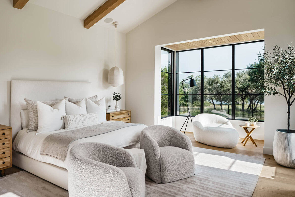 Primary bedroom with boucle chairs and floor-to-ceiling black-framed windows