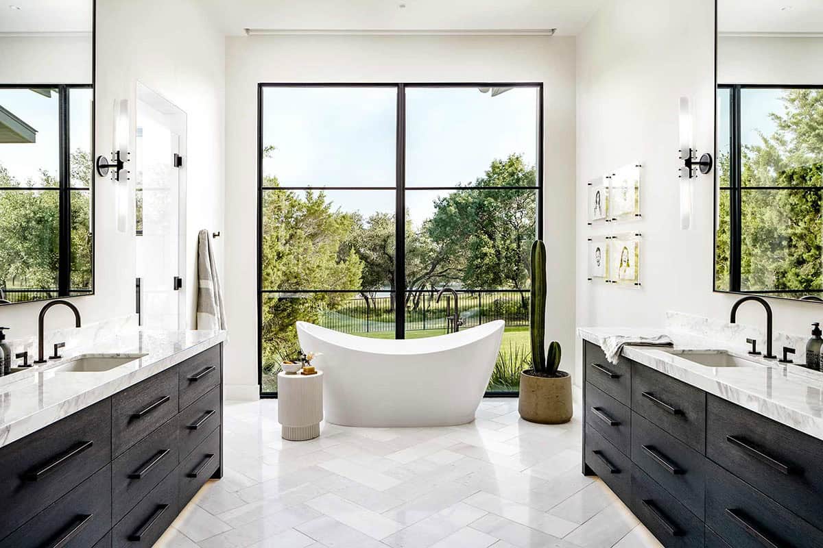 Freestanding tub centered beneath tall steel-framed bathroom window