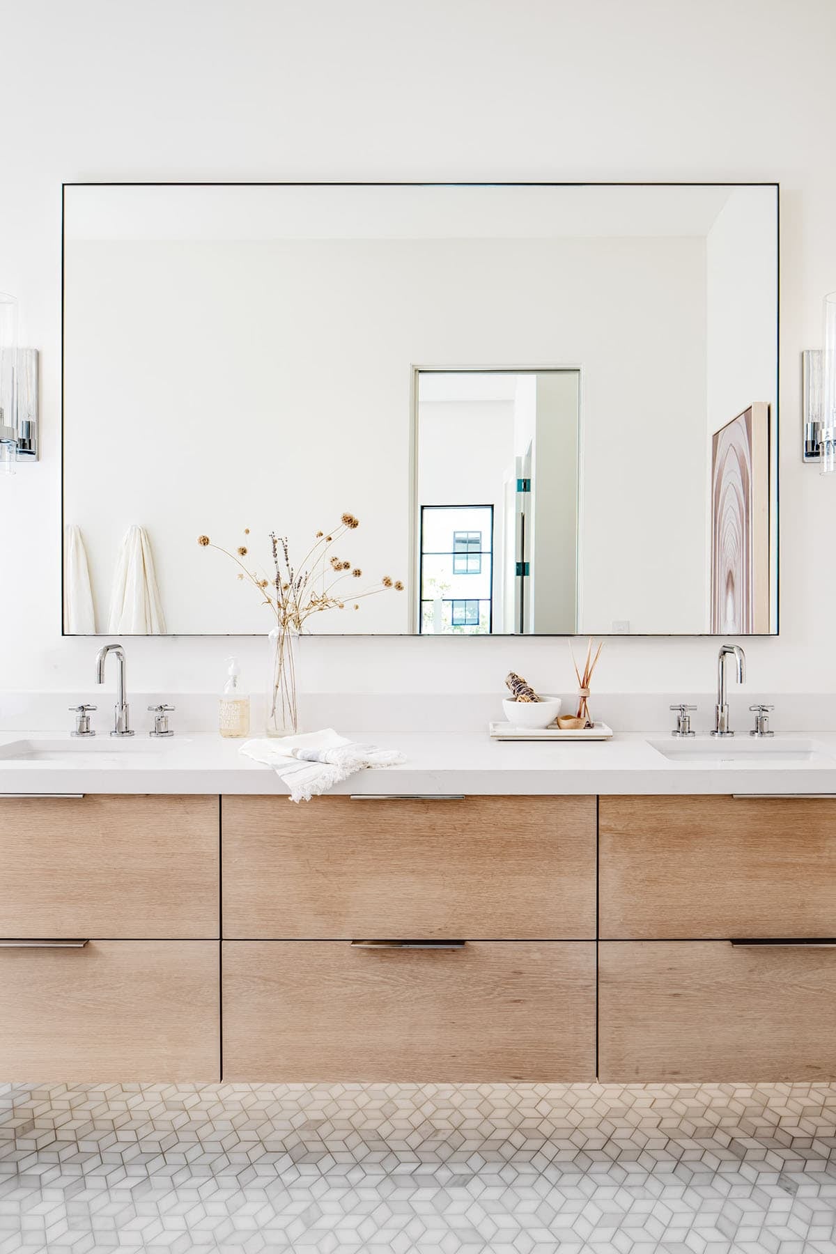 Double vanity with white oak cabinetry and large frameless mirror