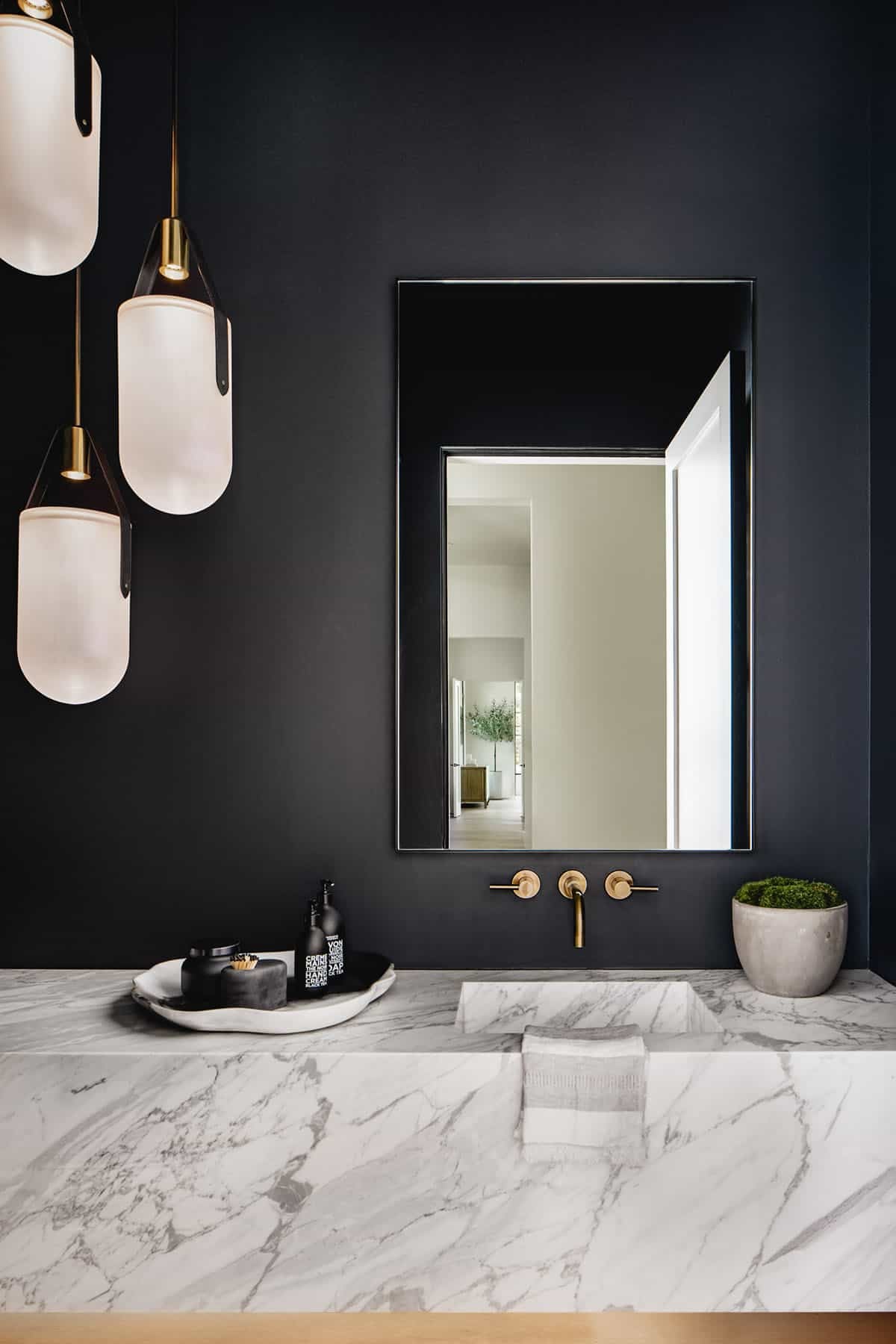 Powder room with matte black walls and brass wall-mounted faucet