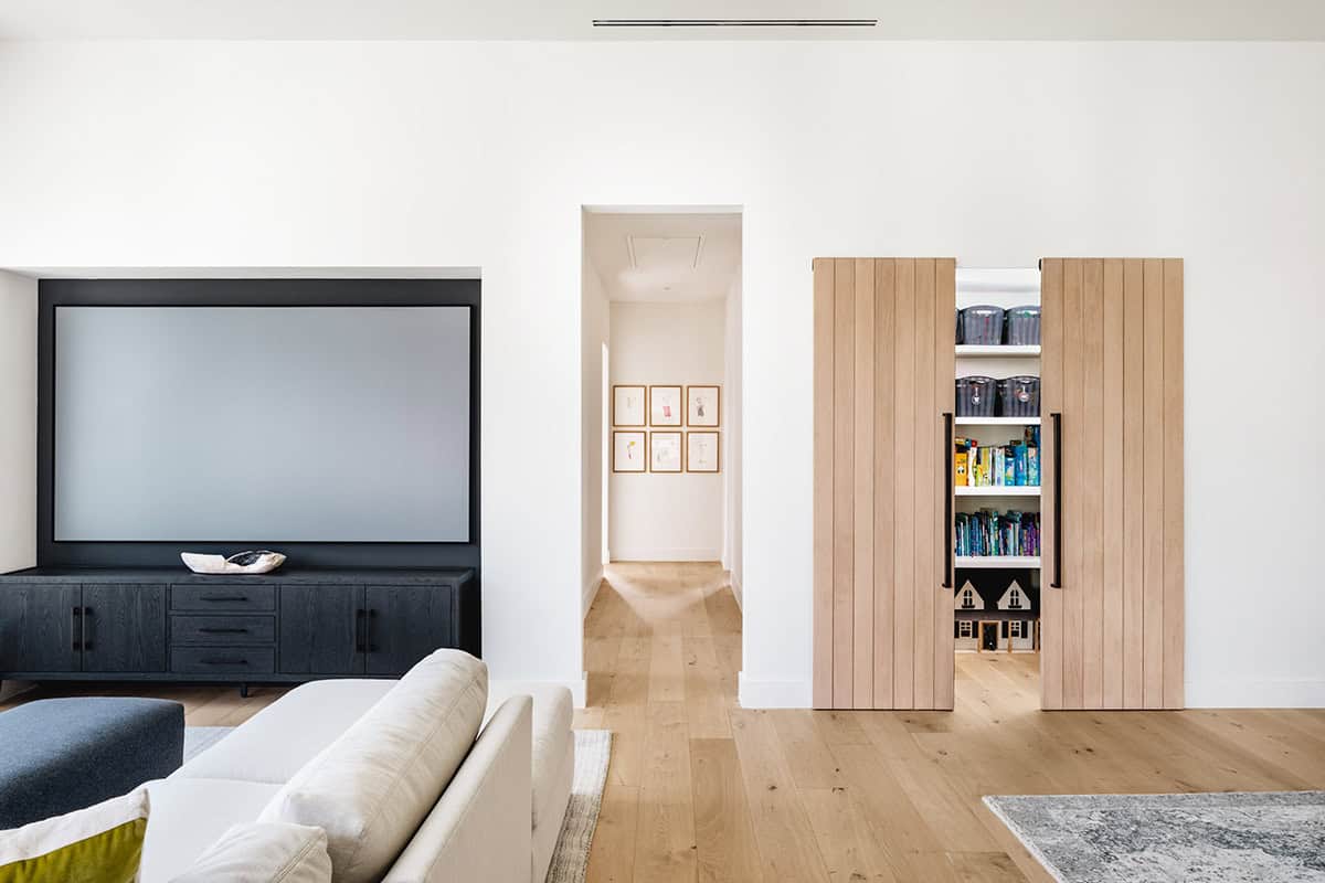 Media wall with sliding oak barn doors revealing playroom storage