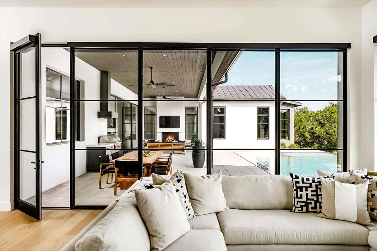 Living area opening through glass doors to covered outdoor kitchen