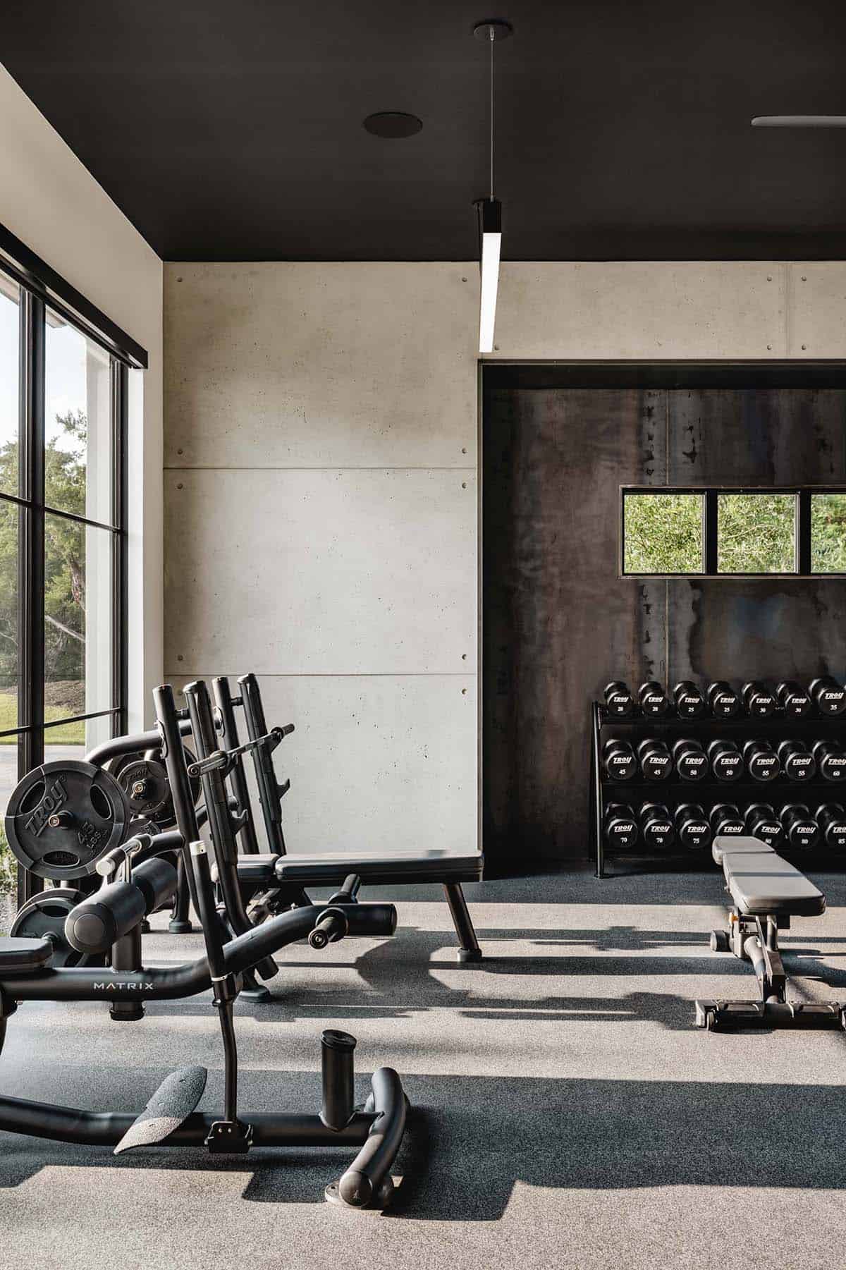 Home gym with concrete panel walls and dumbbell storage rack