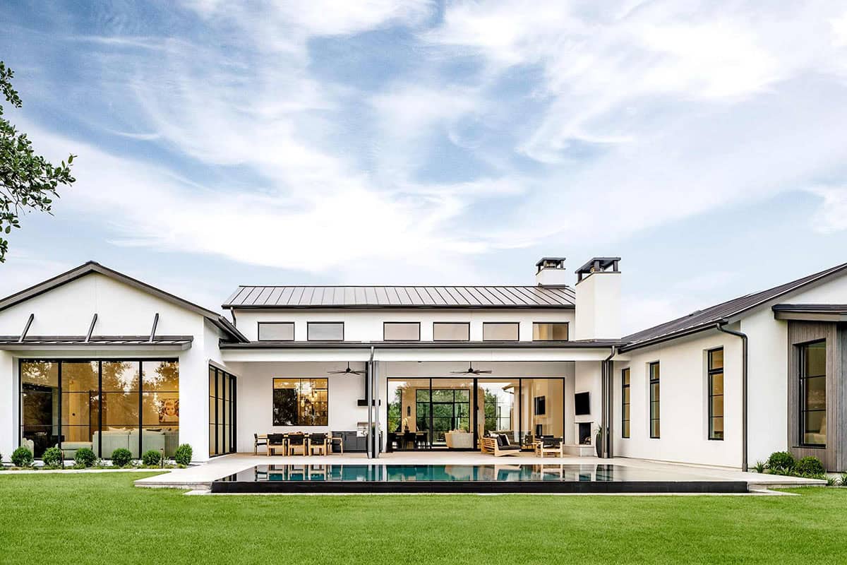 Backyard view of pool, lawn, and multi-gabled metal roof