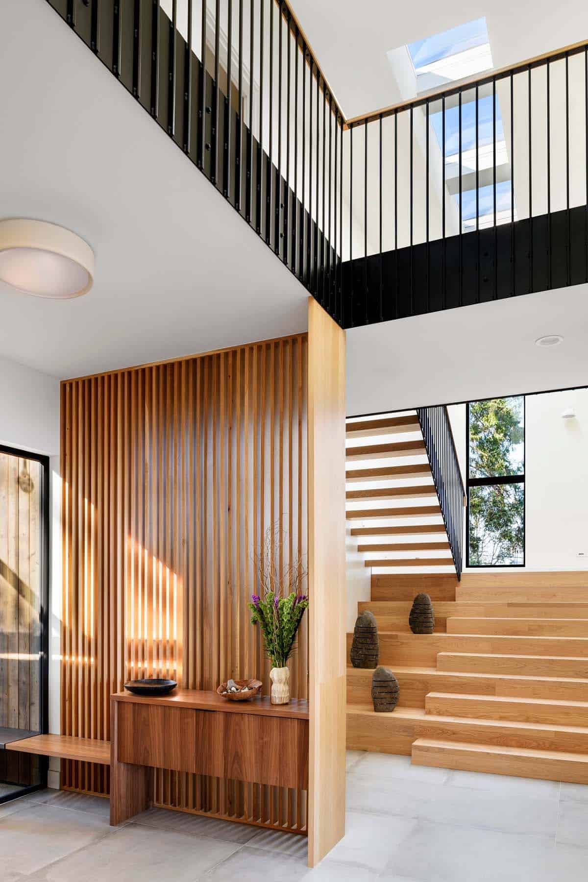 Floating oak stair treads rise past skylights and black railings