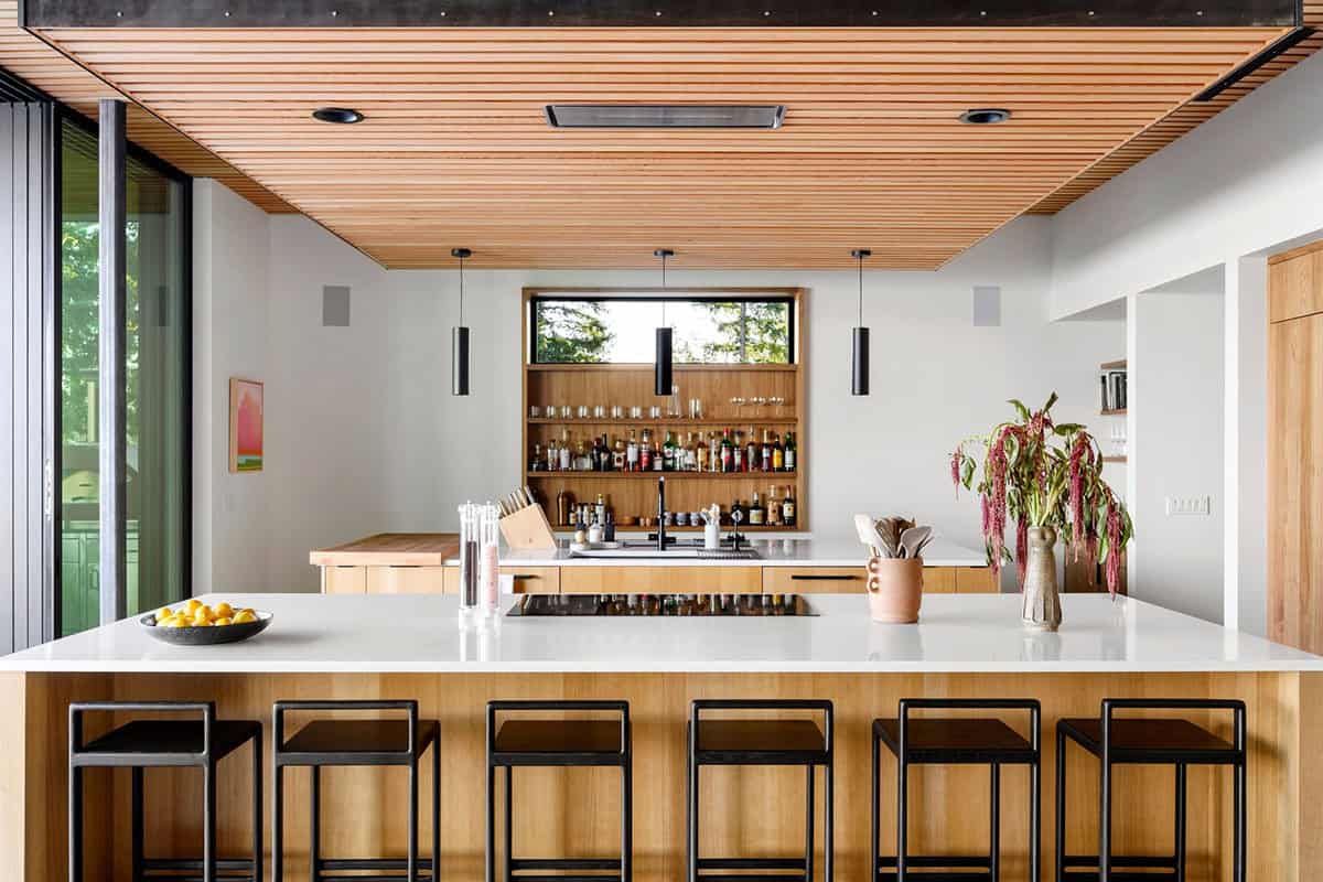Kitchen island view toward open shelving and built-in bar display