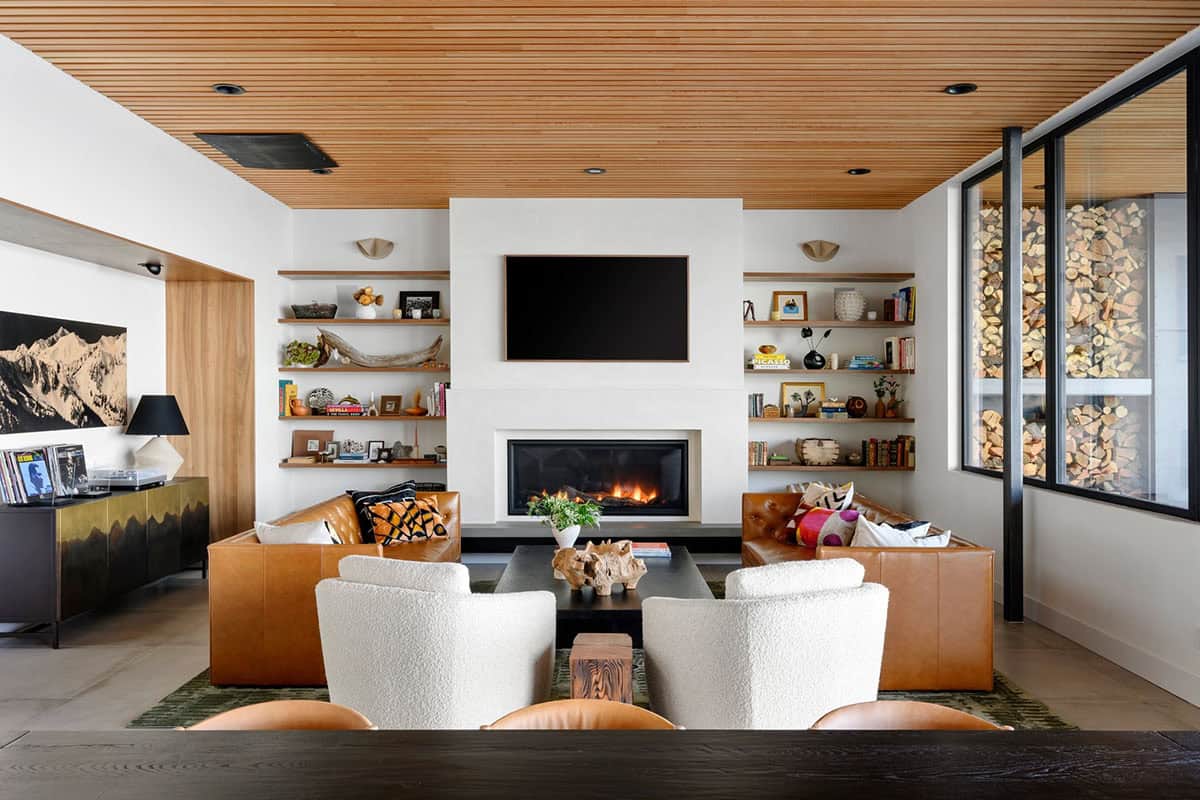 Living room fireplace flanked by open shelving and leather sofas