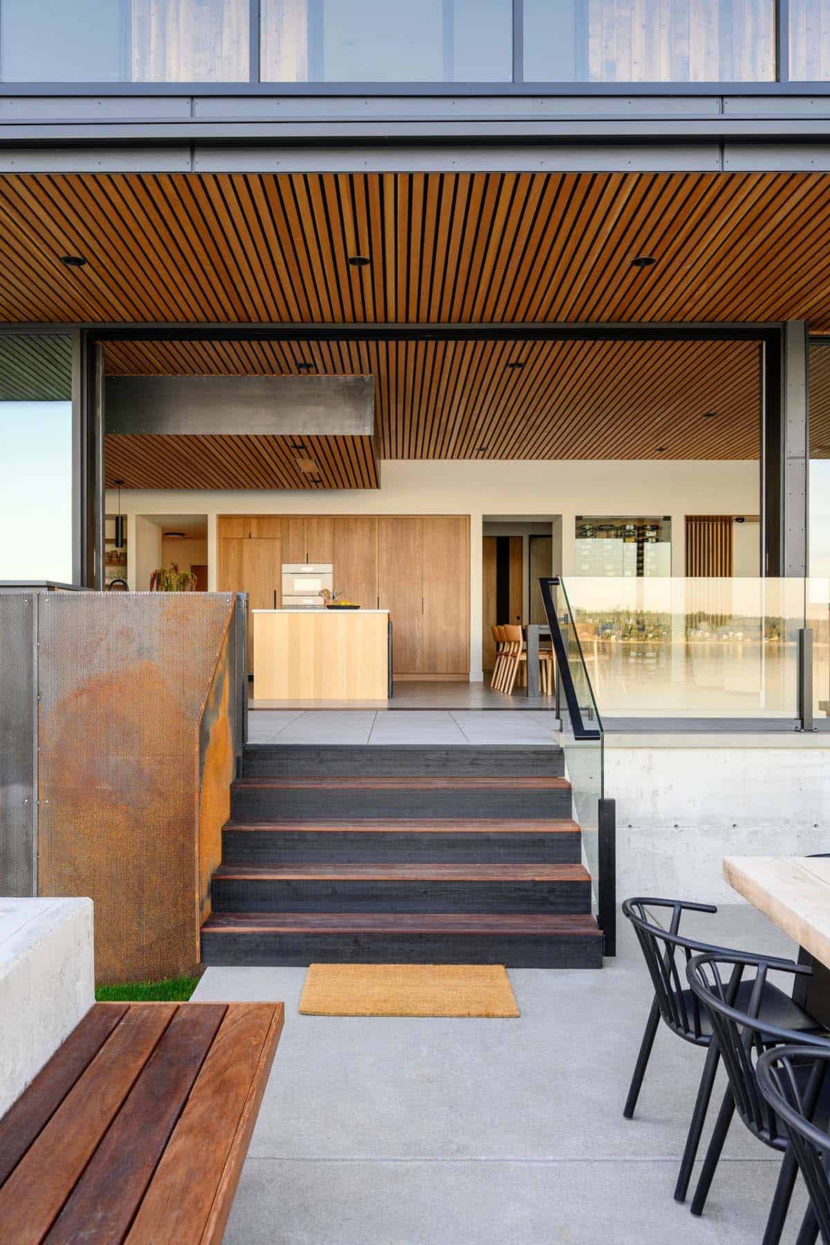Wood-clad stairway leads from patio into open kitchen and dining