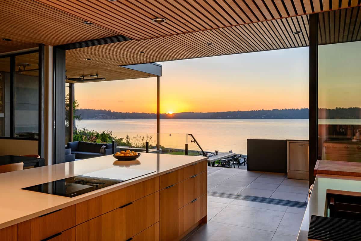 Kitchen island frames sunset view over water through open walls