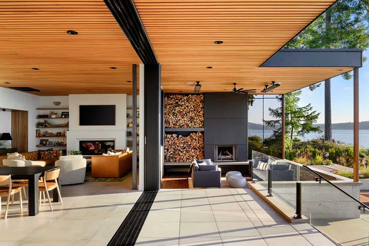 Open-air living room ceiling frames water view past firewood wall
